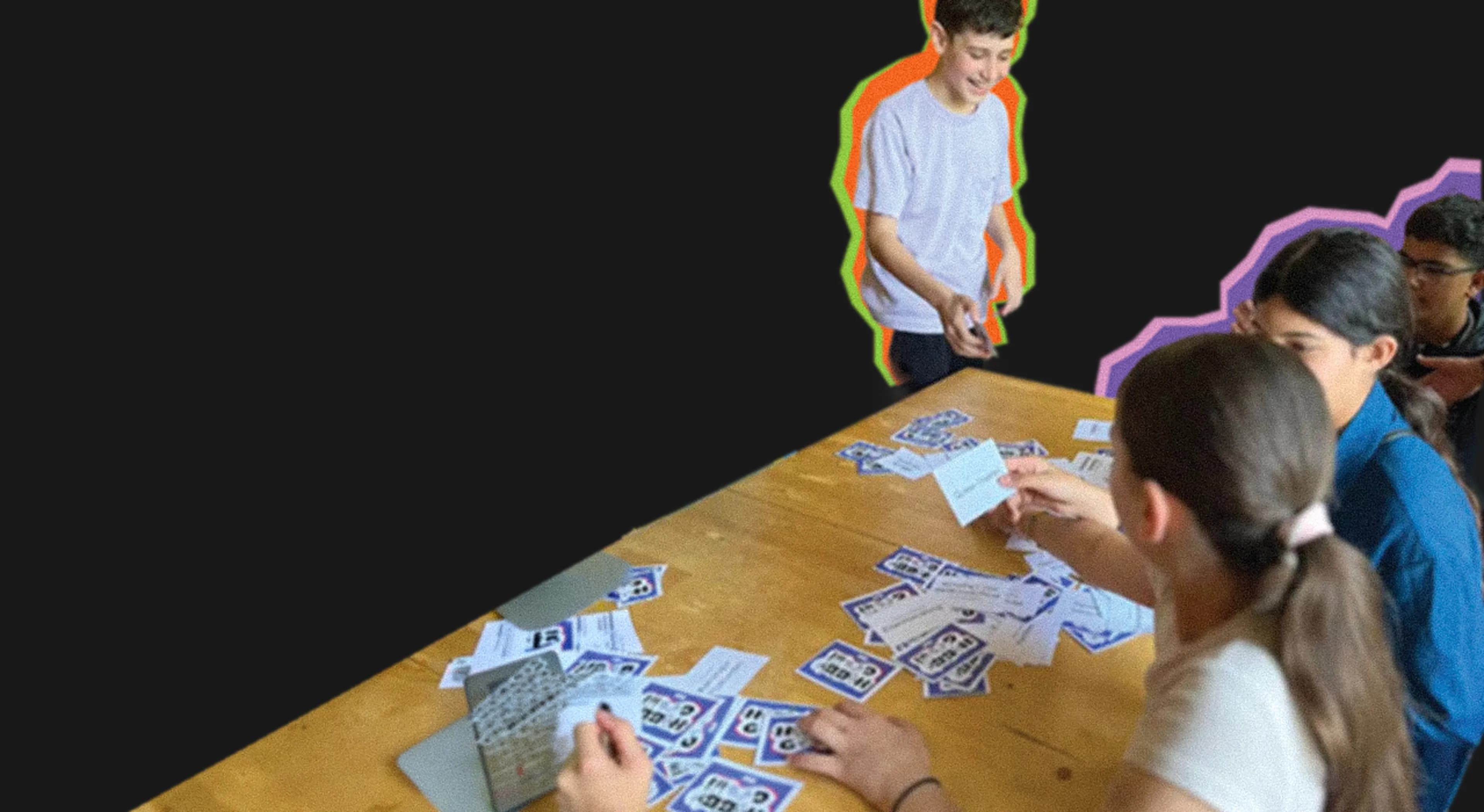 Schuelerinnen und Schueler spielen Karten an einem Tisch